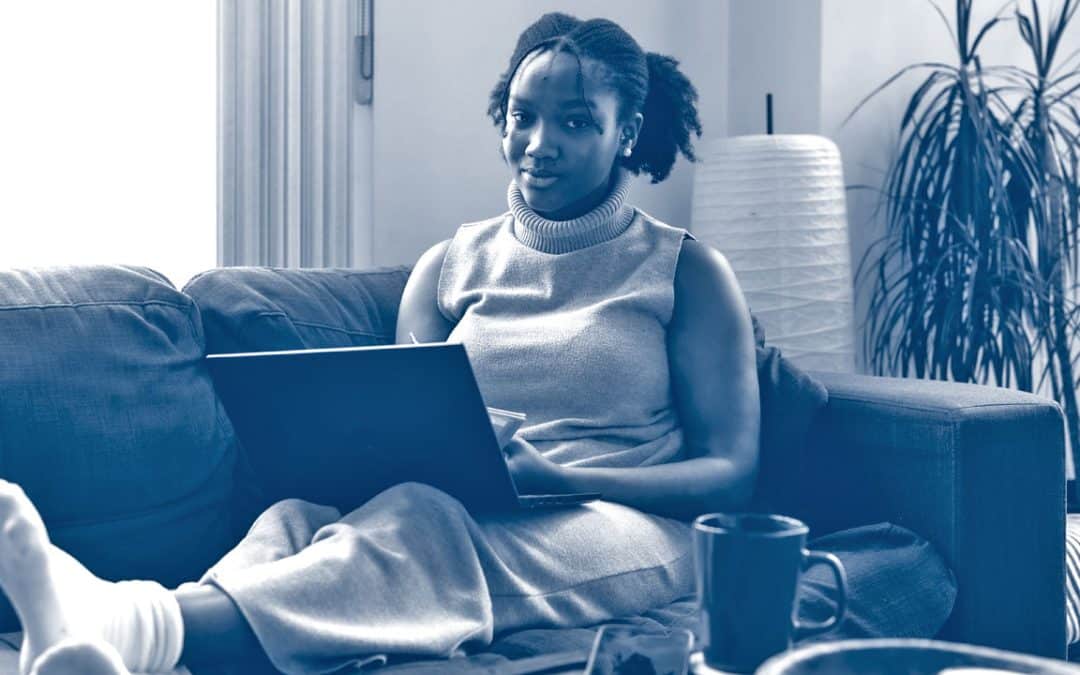 femme sur un canapé travaillant avec son ordinateur portable, illustration des facilités qu'offre la formation professionnelle en ligne